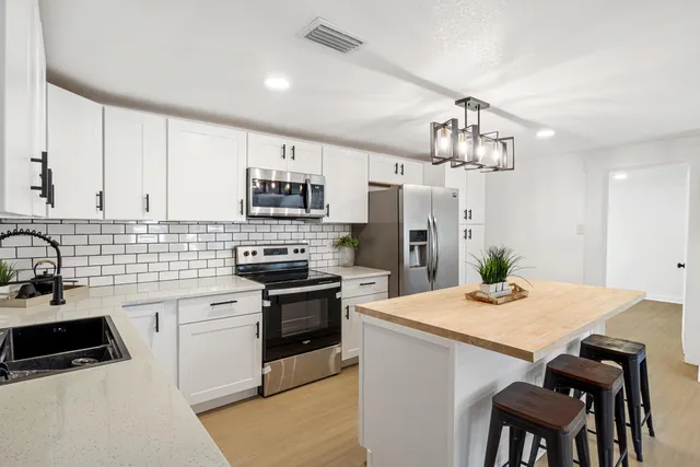 a kitchen with a sink a kitchen island and stainless steel appliances
