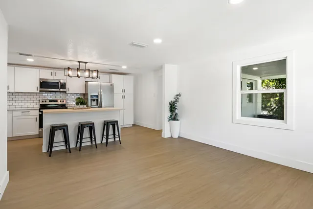 a kitchen with kitchen island a dining table chairs and a refrigerator