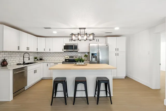 a kitchen with stainless steel appliances a table chairs refrigerator and a cabinets