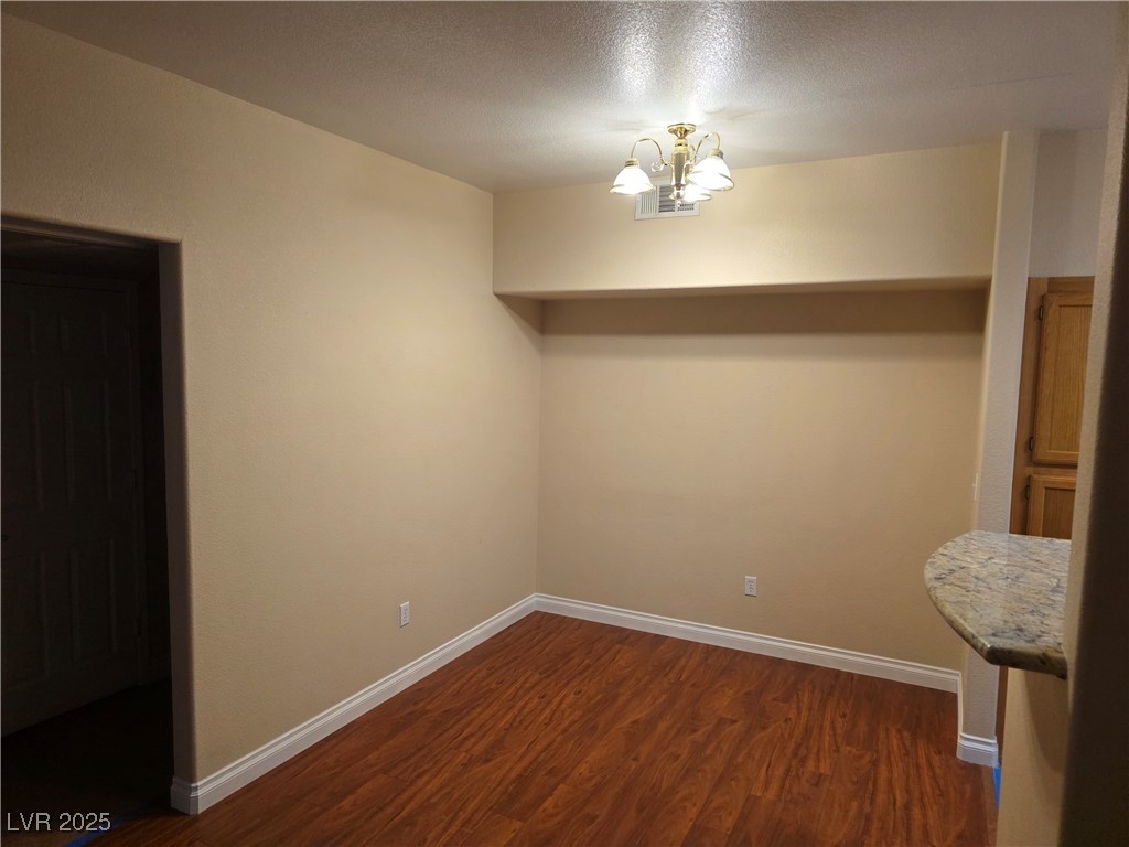 7255 West Sunset Road, Unit 1171 Las Vegas, NV 89113 - Photo 5 of 12 Unfurnished dining area featuring dark wood-style floors, baseboards, and a chandelier