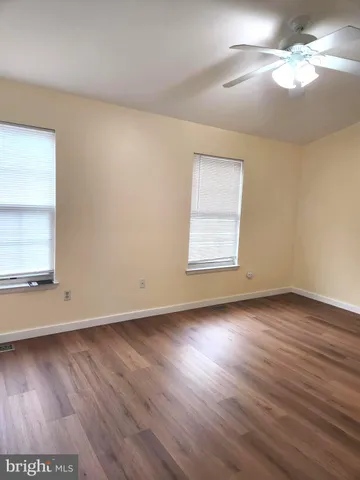 an empty room with wooden floor chandelier fan and windows