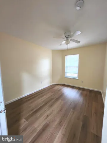 an empty room with wooden floor ceiling fan and windows