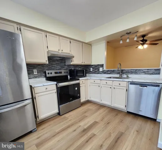 a kitchen with a white cabinets a sink a window and stainless steel appliances