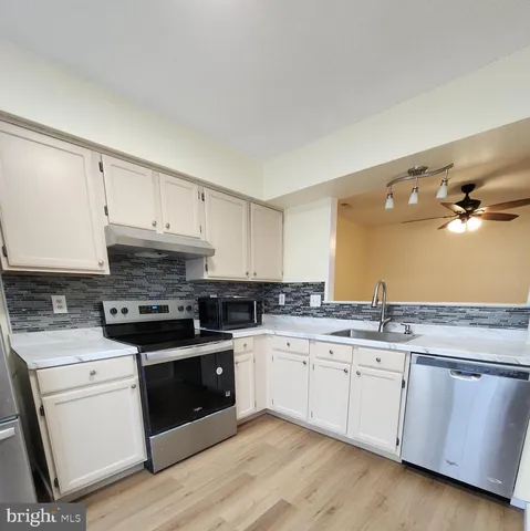 a kitchen with granite countertop white cabinets and white appliances