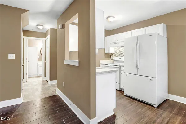 a view of a hallway with wooden floor and cabinets