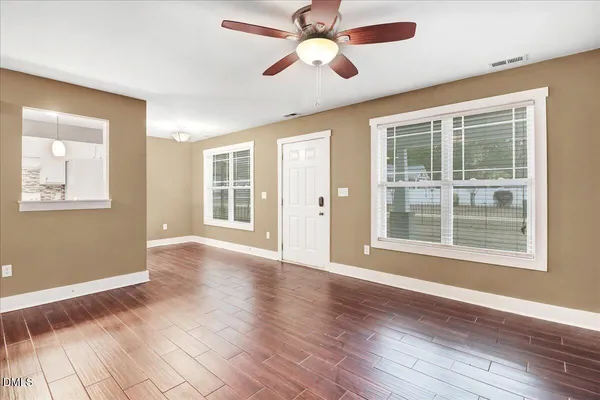 a view of an empty room with a window and wooden floor