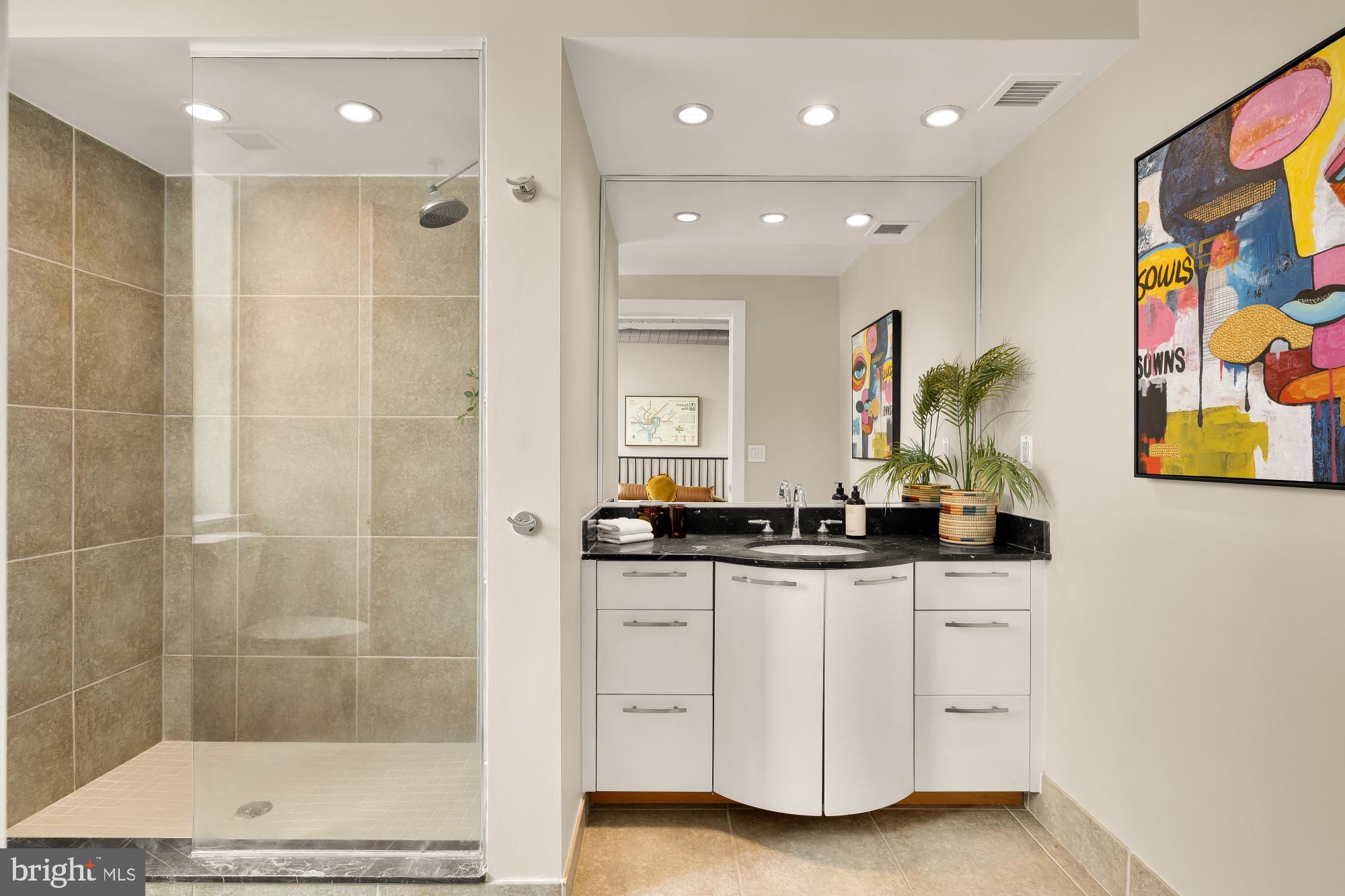 916 G St. Northwest, Unit 806 Washington, DC 20001 - Photo 15 of 19 a bathroom with a granite countertop sink a mirror a shower and a bathtub