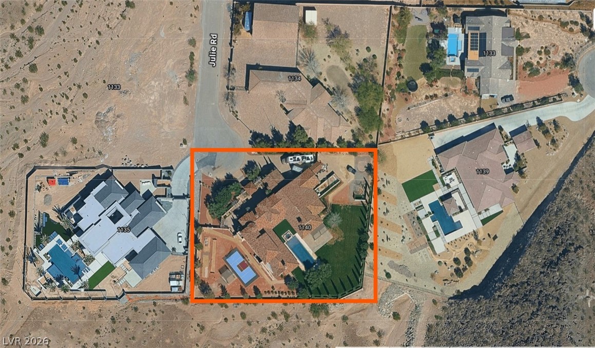 1140 Julie Road Henderson, NV 89002 - Photo 1 of 71 An aerial perspective reveals a luxurious desert estate featuring a spacious main residence, two inviting pools, and a tennis court.