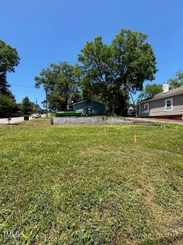 a view of a large yard with plants and large trees