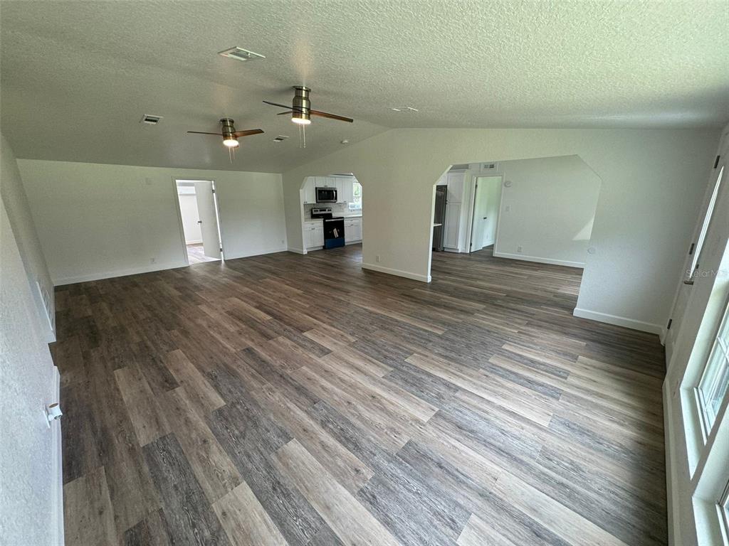4970 Harrison Road Mims, FL 32754 - Photo 7 of 30 an empty room with wooden floor and kitchen view