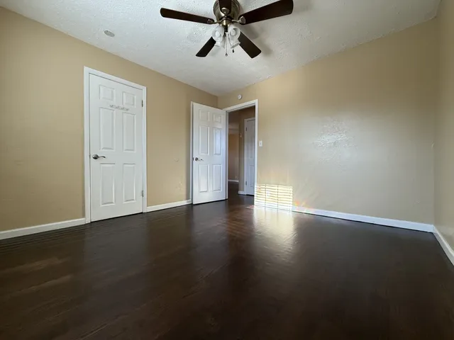 a view of empty room with wooden floor and fan
