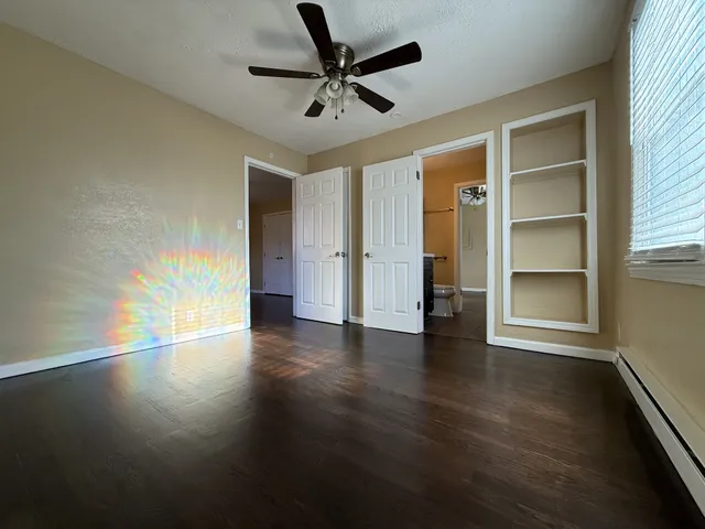 an empty room with wooden floor closet and windows