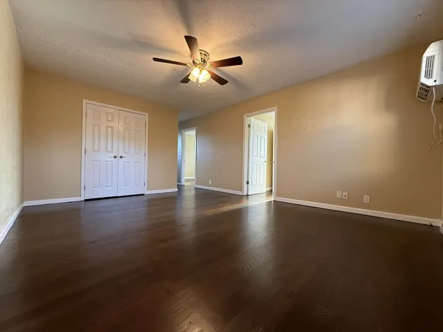 a view of an empty room with wooden floor and window