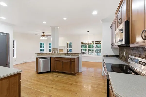 a large kitchen with granite countertop a stove top oven a sink a dining table and chairs