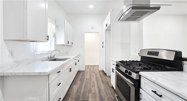 a kitchen with granite countertop a sink stove and cabinets