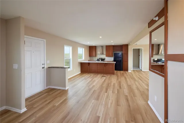 a view of empty room with wooden floor and kitchen