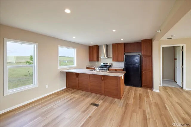 a kitchen with stainless steel appliances granite countertop a refrigerator a sink a stove a microwave and with wooden floors