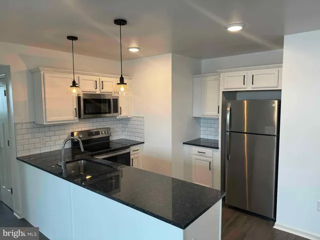 a kitchen with stainless steel appliances granite countertop a refrigerator a sink a stove and microwave