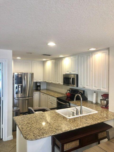 1836 Jeaga Drive Jupiter, FL 33458 - Photo 2 of 20 a kitchen with kitchen island granite countertop a sink stove and refrigerator