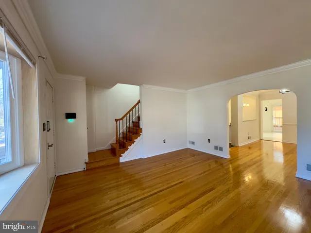 a view of an empty room with wooden floor and stairs
