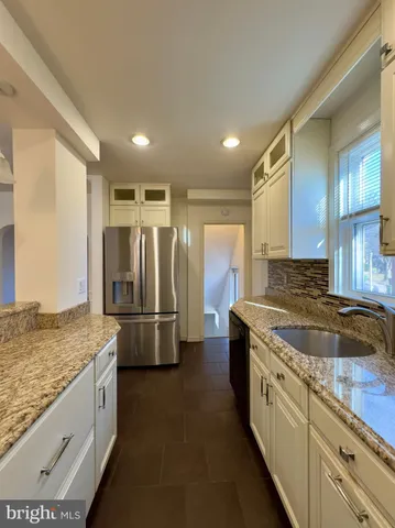 a kitchen with stainless steel appliances granite countertop a sink and a refrigerator