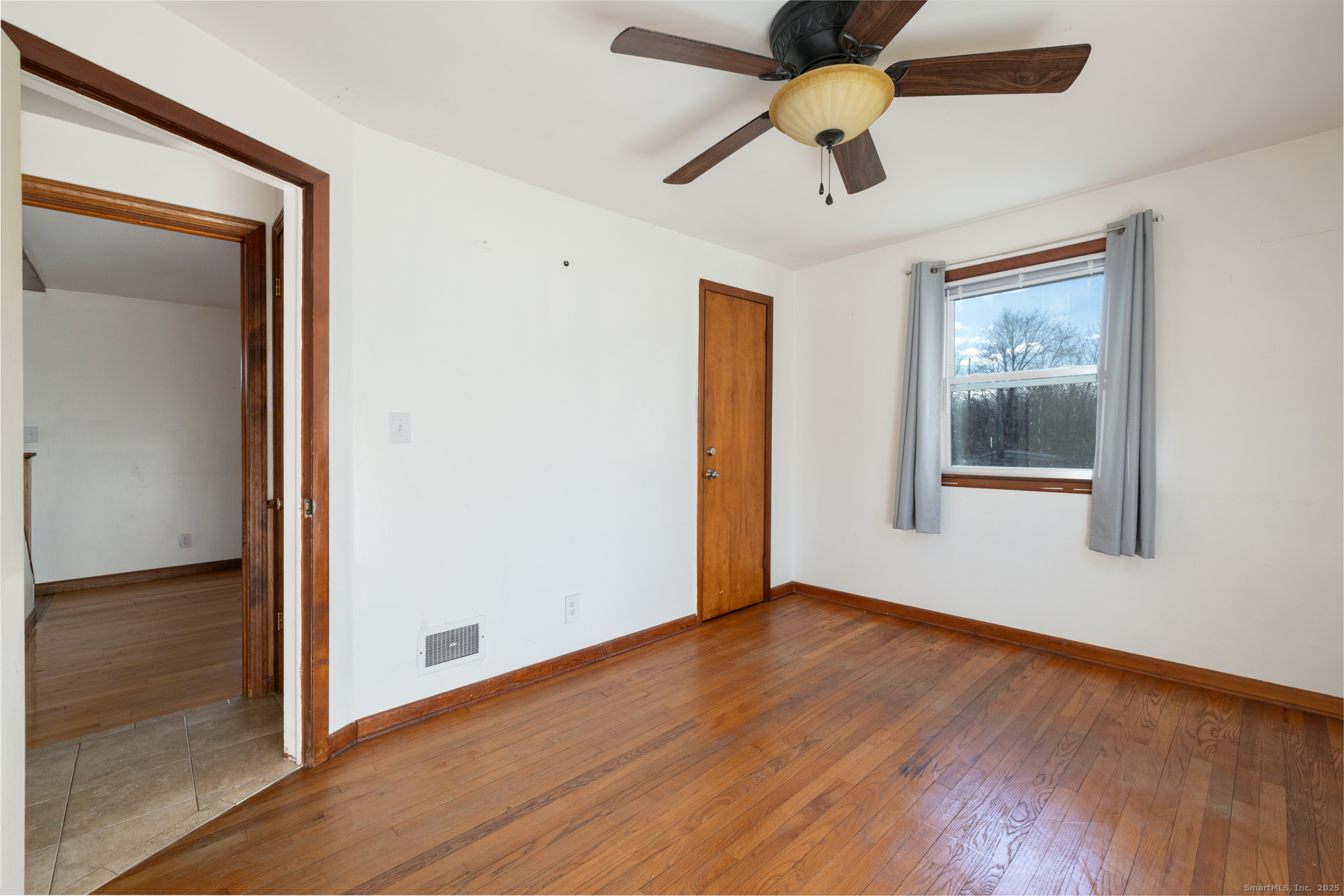 a view of an empty room with window and wooden floor