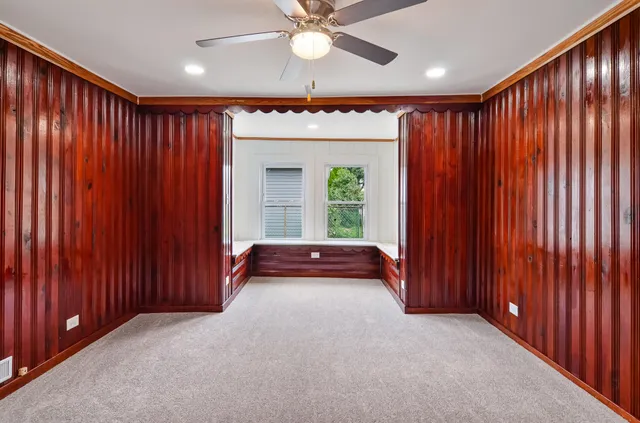 an empty room with windows and chandelier fan