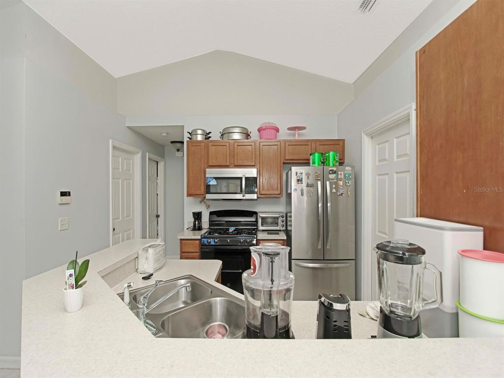 6936 Needle Point Drive Orlando, FL 32822 - Photo 12 of 29 a kitchen with stainless steel appliances kitchen island granite countertop a refrigerator and a stove top oven