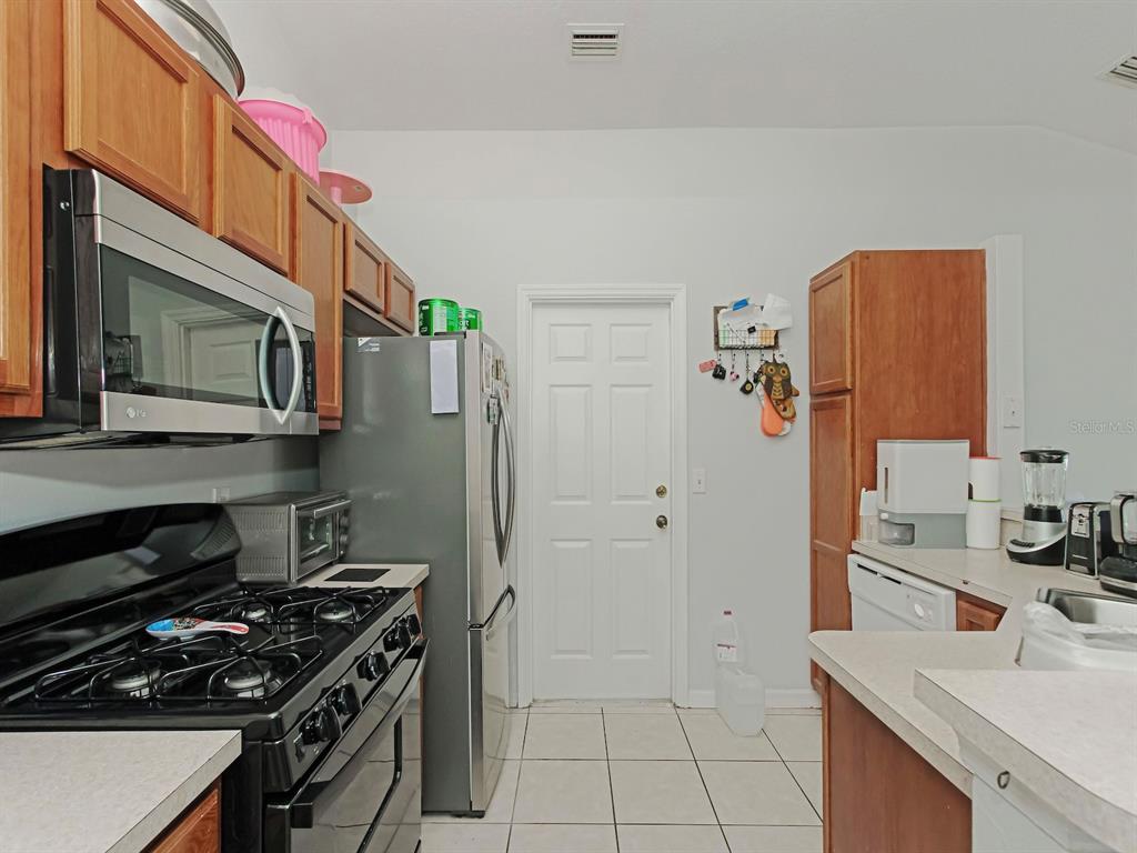 6936 Needle Point Drive Orlando, FL 32822 - Photo 10 of 29 a kitchen with stainless steel appliances granite countertop a stove and a microwave