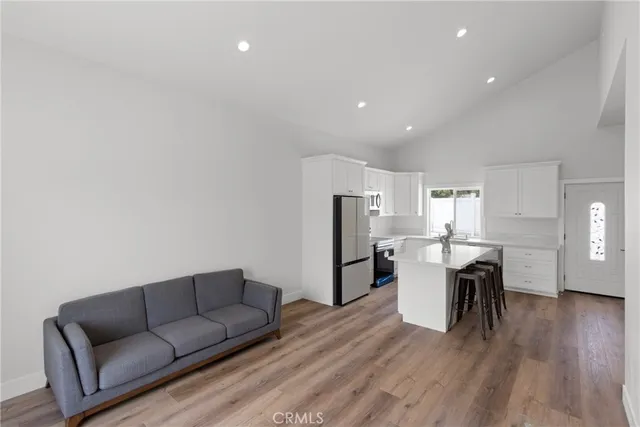 a living room with stainless steel appliances furniture a dining table and wooden floor