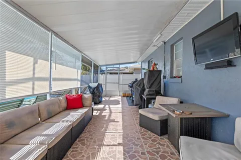 a living room with furniture a flat screen tv and a floor to ceiling window