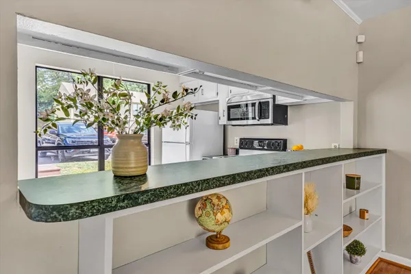a view of an empty room with kitchen and window