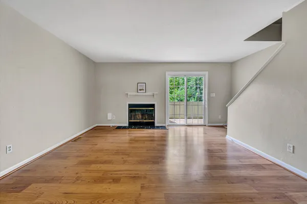 an empty room with wooden floor fireplace and windows