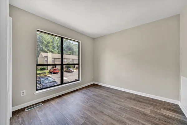 a view of an empty room with window and wooden floor