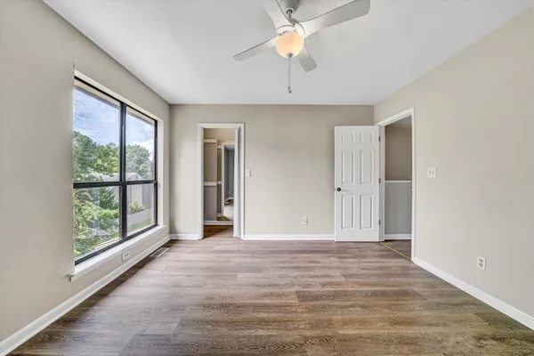 a view of an empty room with wooden floor and a window