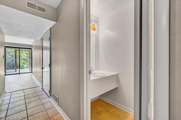 a view of an empty room with wooden floor and a bathroom