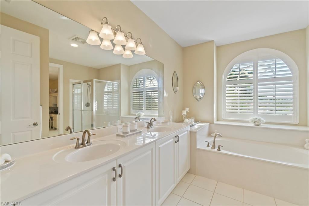 1879 Ivory Cane Point Naples, FL 34119 - Photo 31 of 49 a spacious bathroom with a sink a large mirror and a bathtub next to a window