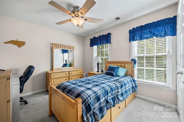a bedroom with a bed a chandelier and dresser