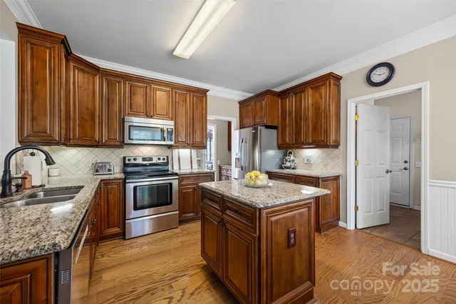 a kitchen with stainless steel appliances granite countertop a sink stove microwave and refrigerator
