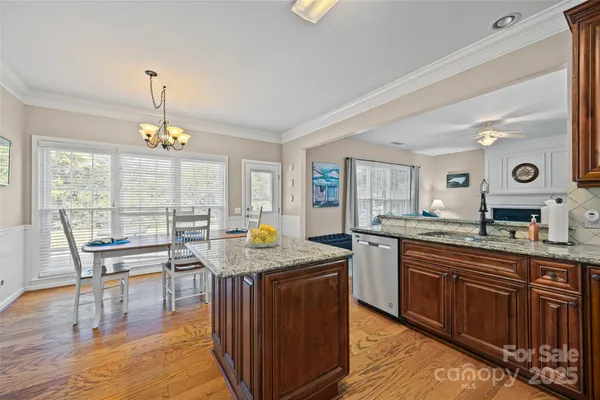 a kitchen with granite countertop a stove a sink dishwasher and a dining table with wooden floor