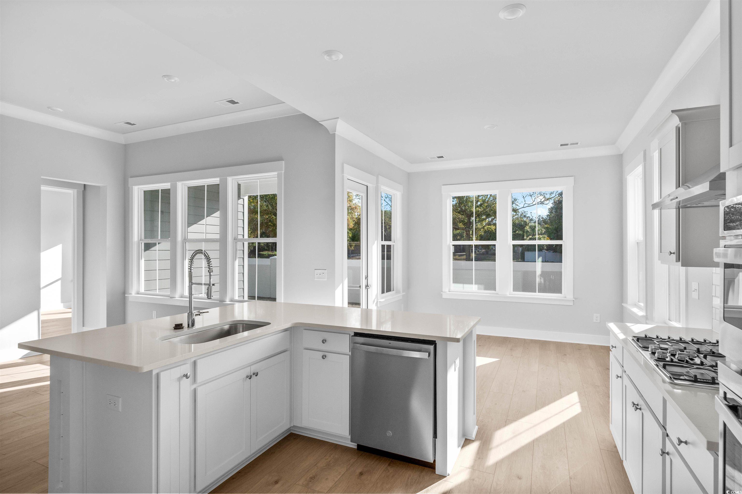 231 Atlantic Breeze Street Myrtle Beach, SC 29572 - Photo 13 of 21 Kitchen featuring white cabinets, ornamental molding, stainless steel appliances, a center island with sink, and healthy amount of natural light