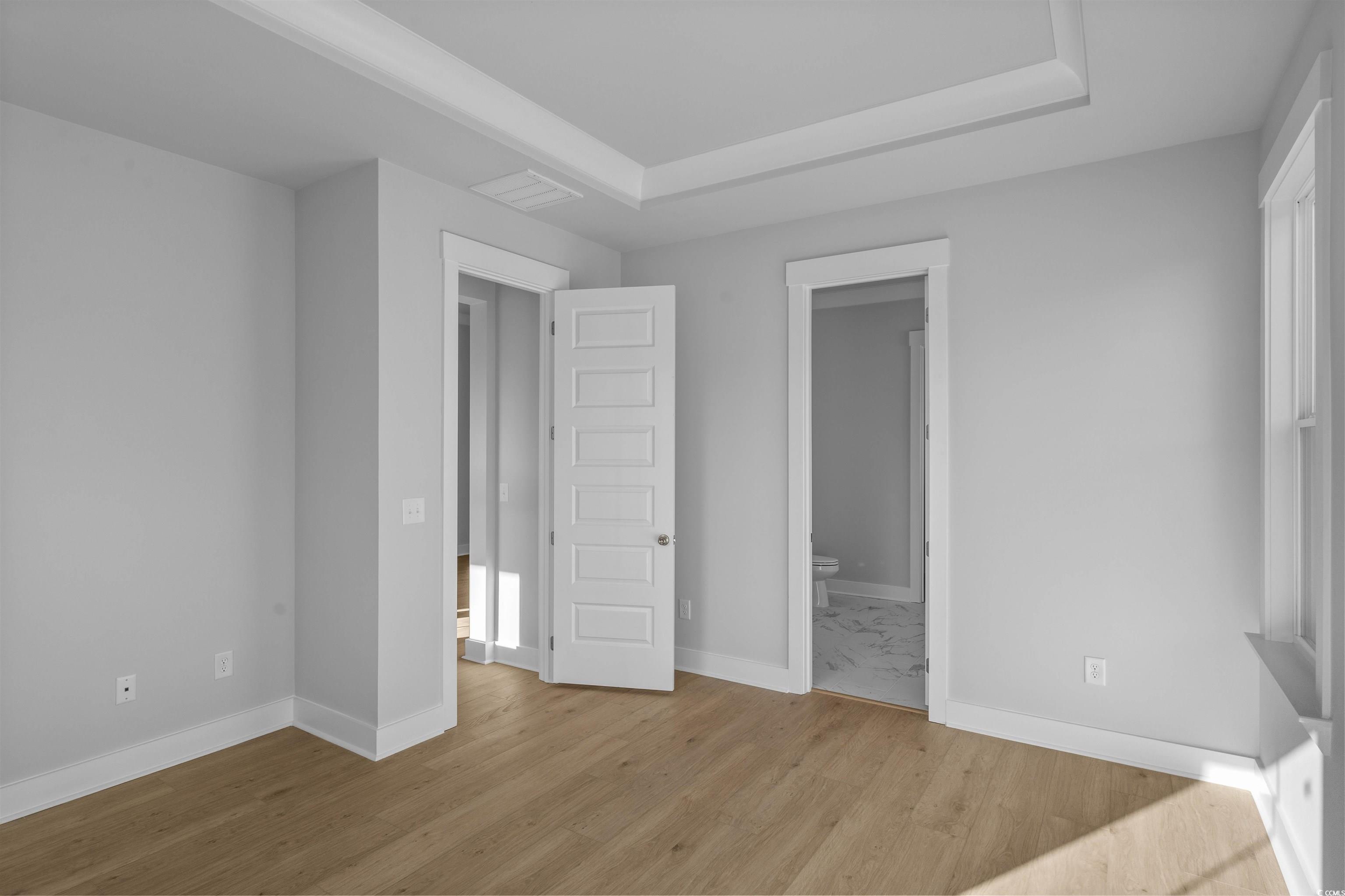 231 Atlantic Breeze Street Myrtle Beach, SC 29572 - Photo 19 of 21 Unfurnished bedroom with ensuite bath, light wood finished floors, and a tray ceiling