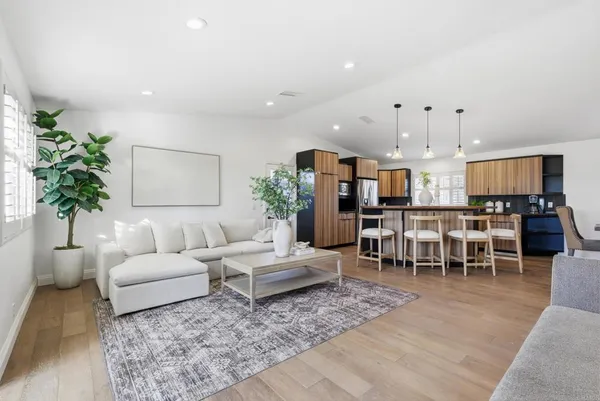 a living room with furniture potted plant and kitchen view