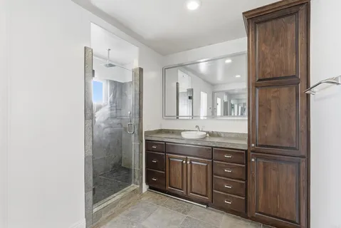 a bathroom with a granite countertop sink mirror and shower