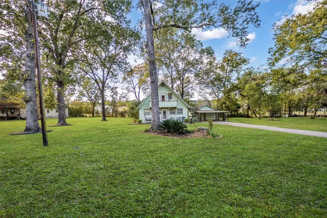 a view of a house with a big yard and large trees