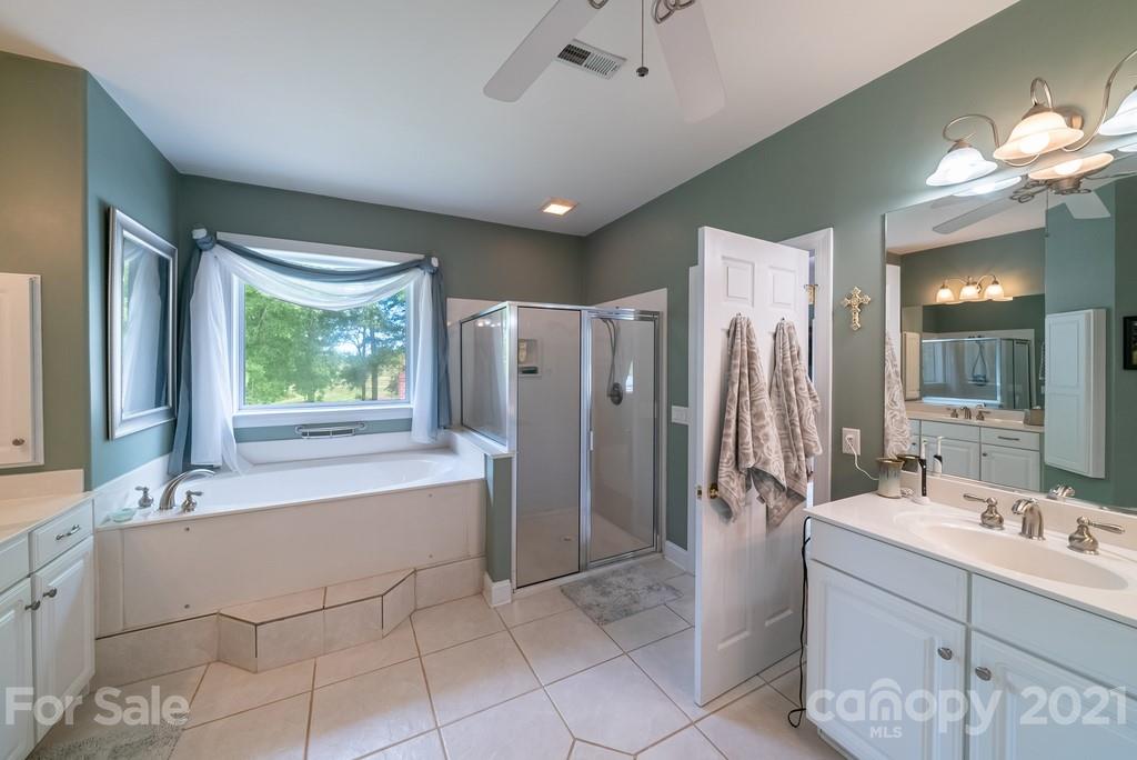 310 Bridle Path Farm Road Cleveland, NC 27013 - Photo 16 of 48 a bathroom with a double vanity sink a large mirror and a bathtub