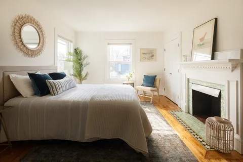 a bed sitting in a bedroom next to a window and a chair