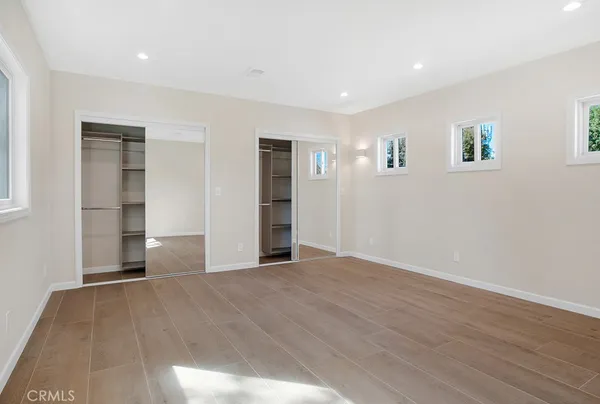 a view of an empty room with wooden floor and closet