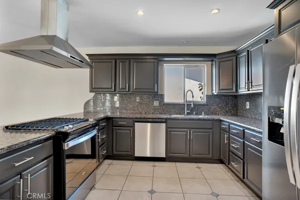a kitchen with stainless steel appliances granite countertop a stove a sink and a refrigerator