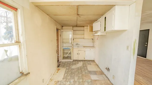 a view of a kitchen with white cabinets and wooden floor